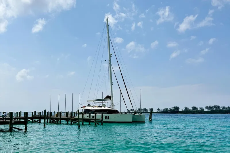 Deo Juvante Yacht Photos Pics 2018 Sunreef 62 ARC catamaran docked in clear turquoise waters under a blue sky.