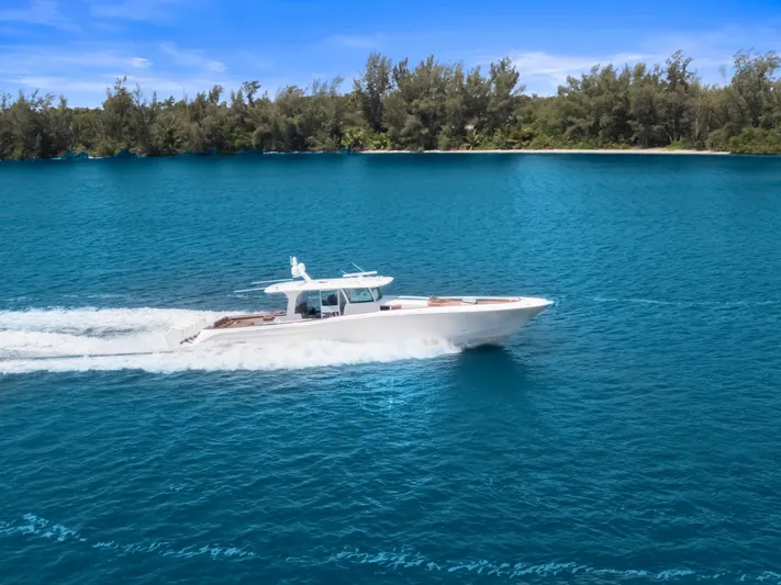 Big Momma Yacht Photos Pics 2023 HCB 65 Estrella cruising on blue water near a forested shoreline.