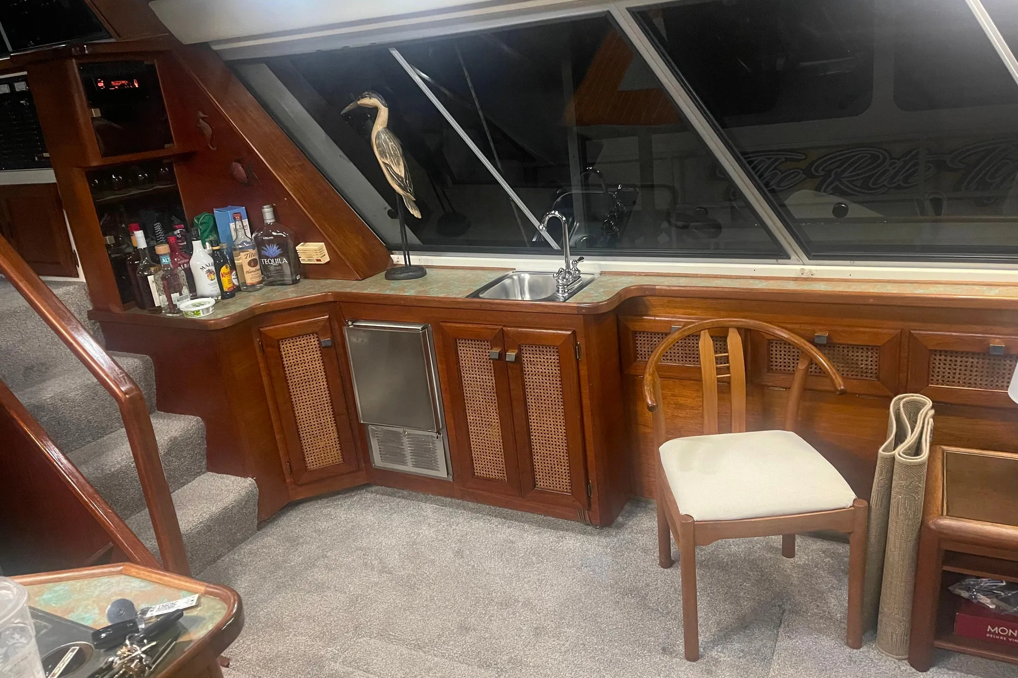 Luxurious interior of 1986 Bayliner 4550 Motoryacht with bar, sink, and wooden chair.