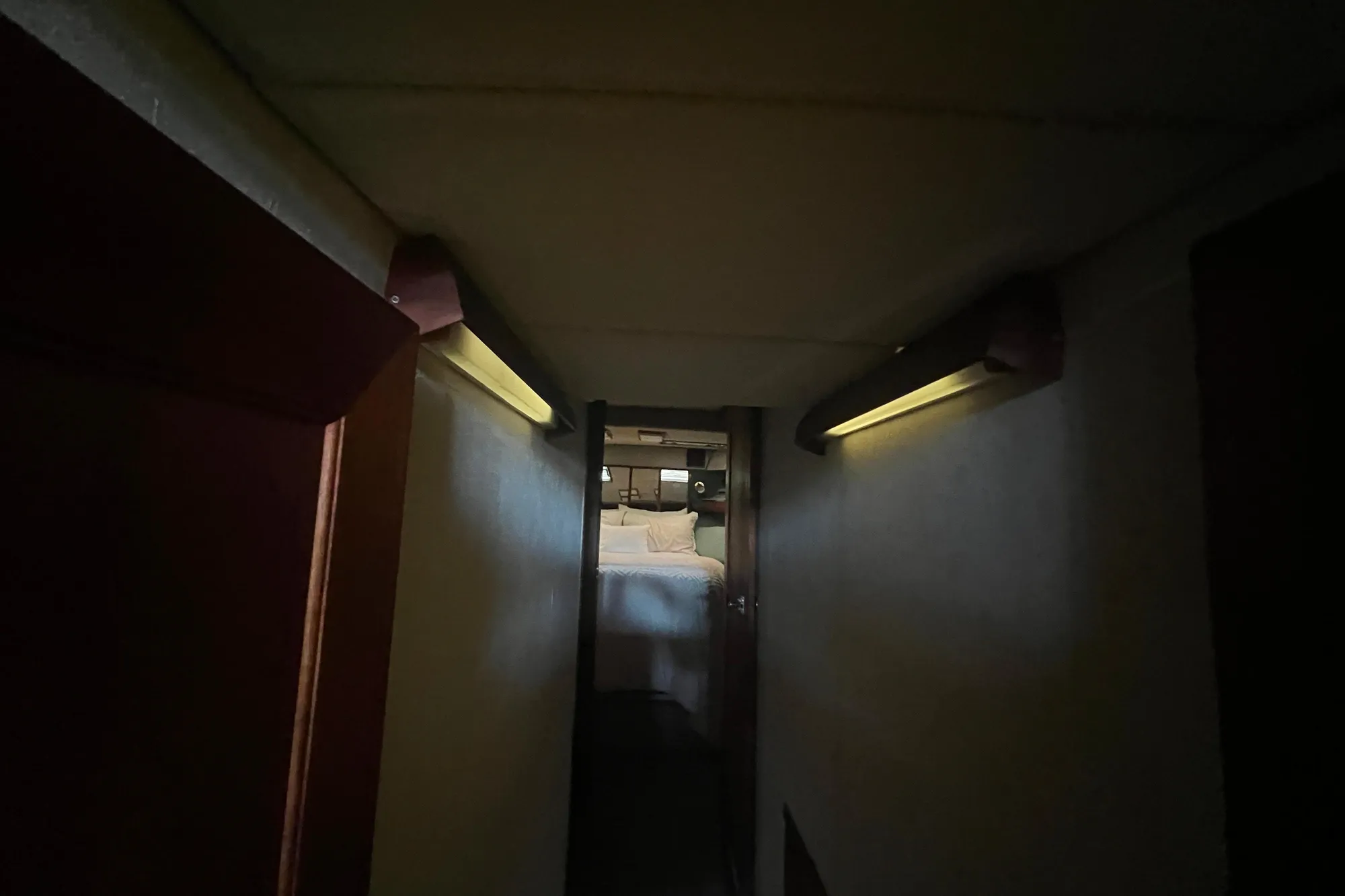 Dimly lit hallway leading to a cozy bedroom in a 1986 Bayliner 4550 Motoryacht.