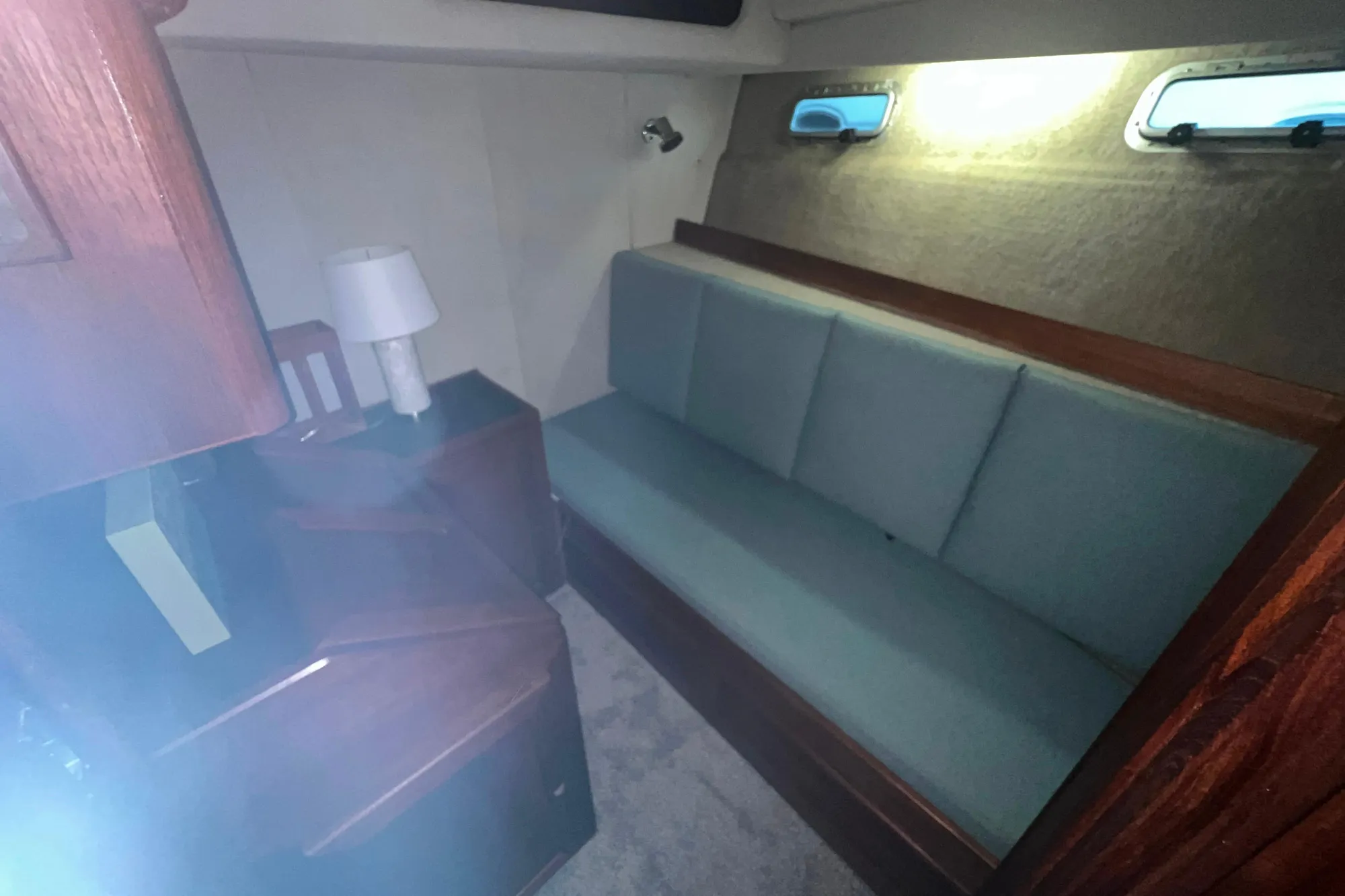 1986 Bayliner 4550 Motoryacht interior with teal sofa, wooden accents, and soft lighting.