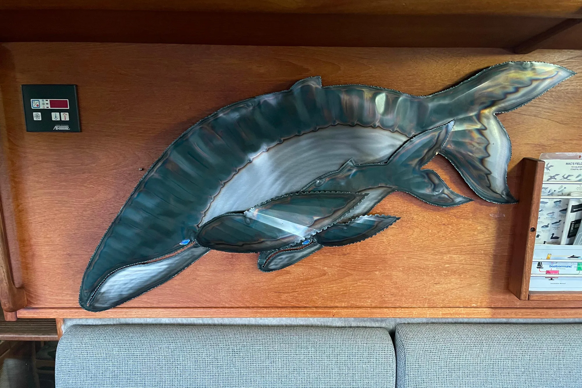 Metal dolphin wall art on 1986 Bayliner 4550 Motoryacht interior wood paneling.