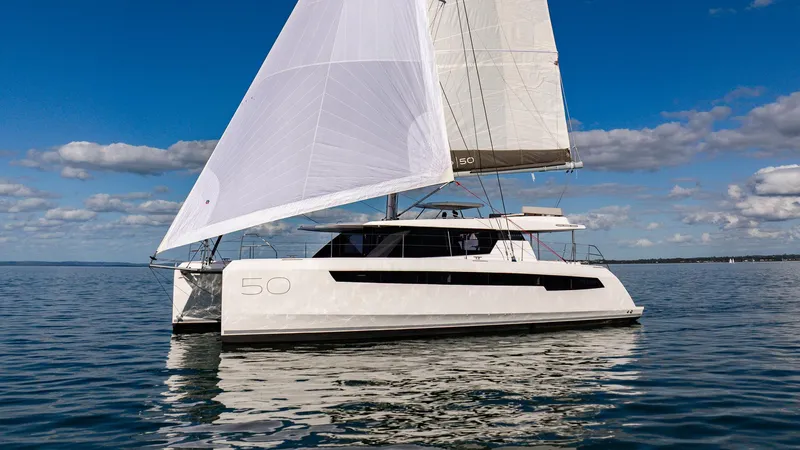  Yacht Photos Pics 2024 Leopard 50 catamaran sailing on calm waters under a clear blue sky.