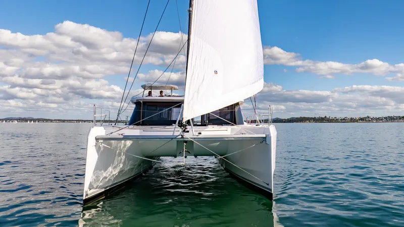  Yacht Photos Pics 2024 Leopard 50 catamaran sailing on calm waters under a clear blue sky.