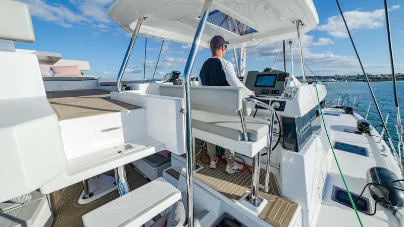  Yacht Photos Pics Man steering 2024 Leopard 50 yacht on open water, clear sky, modern design.