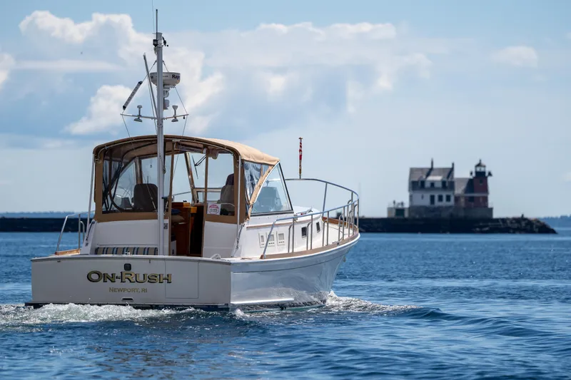 On-rush Yacht Photos Pics Grand Banks Eastbay 43 Ex 2000 boat cruising near a lighthouse on a sunny day.