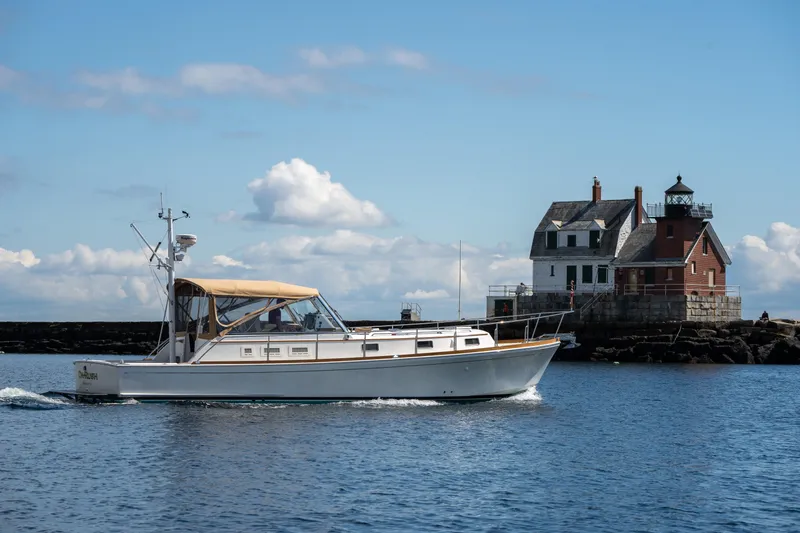 On-rush Yacht Photos Pics Grand Banks Eastbay 43 Ex 2000 cruising near a coastal lighthouse.
