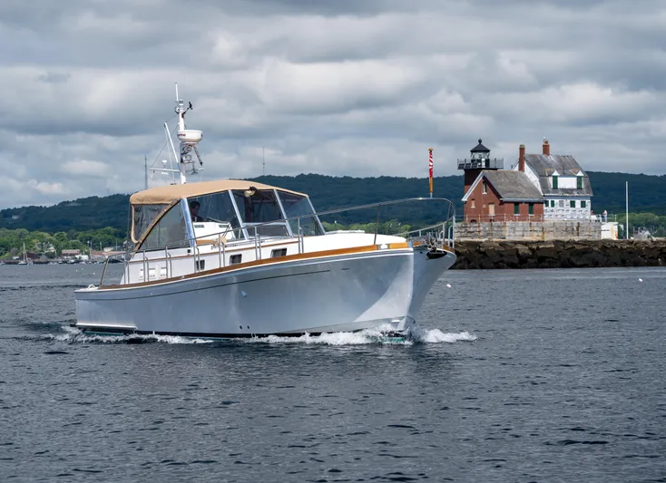 On-rush Yacht Photos Pics Grand Banks Eastbay 43 Ex 2000 cruising near a coastal lighthouse.