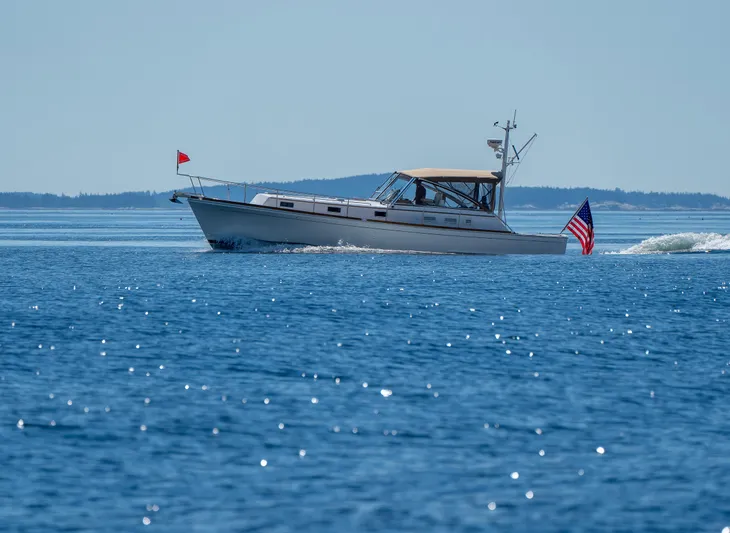 On-rush Yacht Photos Pics Grand Banks Eastbay 43 Ex 2000 cruising on a calm blue sea with American flag.