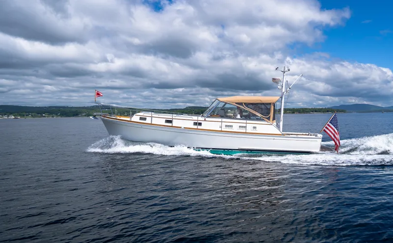 On-rush Yacht Photos Pics Grand Banks Eastbay 43 Ex 2000 cruising on a lake under a partly cloudy sky.
