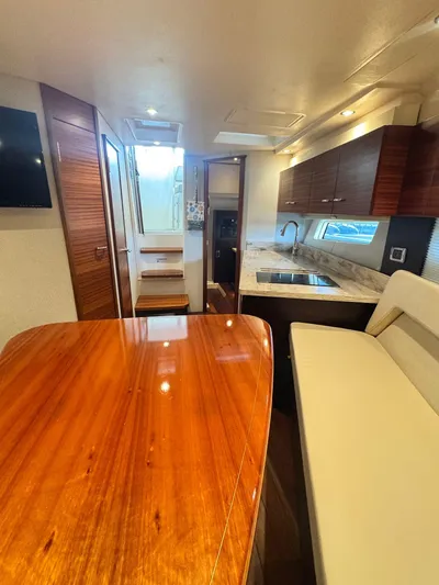  Yacht Photos Pics Luxurious interior of 2016 Pursuit SC 365i Sport Coupe with wooden table and modern kitchen.