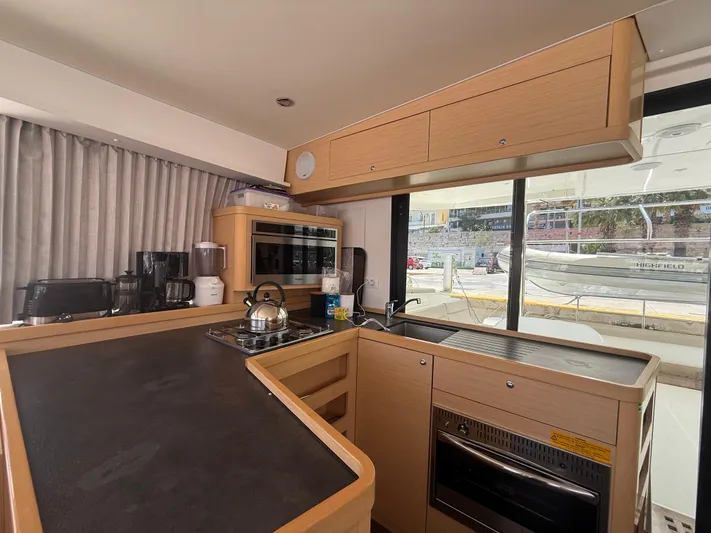 La Mer Yacht Photos Pics Modern kitchen interior of 2020 Lagoon 42 yacht with appliances and wooden cabinetry.