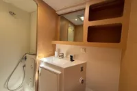 Modern bathroom in 2020 Lagoon 42 yacht with shower, sink, and wooden shelving.
