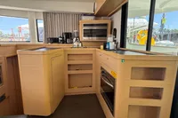 Modern kitchen interior of 2020 Lagoon 42 catamaran with appliances and wooden cabinetry.