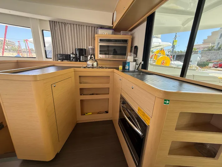 La Mer Yacht Photos Pics Modern kitchen interior of 2020 Lagoon 42 catamaran with appliances and wooden cabinetry.