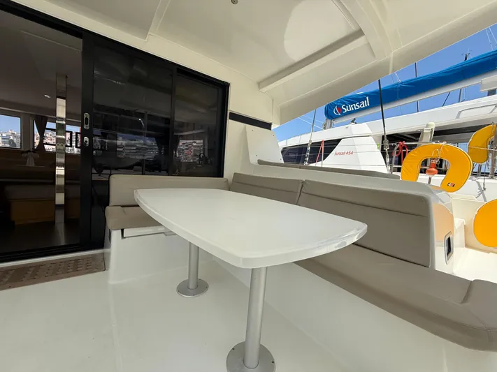 La Mer Yacht Photos Pics Outdoor seating area on a 2020 Lagoon 42 catamaran with table and cushioned benches.