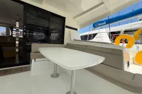 Outdoor seating area on a 2020 Lagoon 42 catamaran with table and cushioned benches.