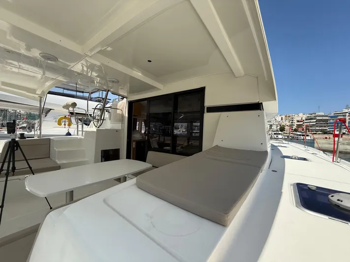 La Mer Yacht Photos Pics 2020 Lagoon 42 catamaran deck with seating and table, docked in a marina.