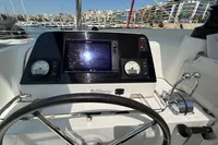 Helm of 2020 Lagoon 42 catamaran with navigation instruments and steering wheel in marina.