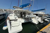 2020 Lagoon 42 catamaran docked at marina, featuring a dinghy and blue sails.