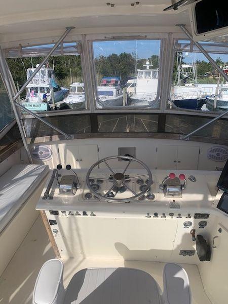 1984 Post Convertible boat cockpit with steering wheel, controls, and marina view. Great deal!