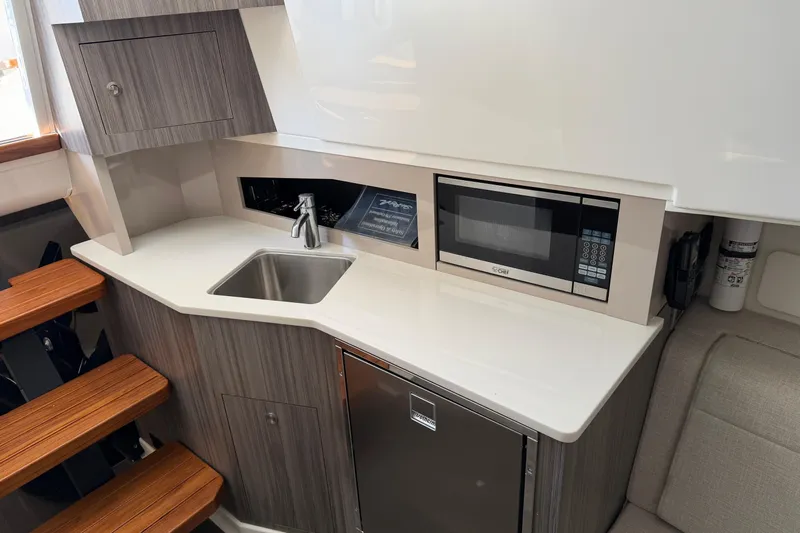 Yacht Photos Pics 2023 Sea Ray Sundancer 370 Outboard interior kitchen with sink, microwave, and wooden steps.