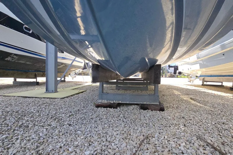  Yacht Photos Pics 2023 Sea Ray Sundancer 370 Outboard hull on gravel, supported by metal stands.