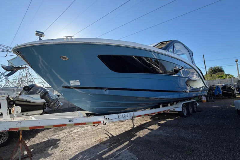  Yacht Photos Pics 2023 Sea Ray Sundancer 370 Outboard on trailer, sleek design, blue hull, sunny day.