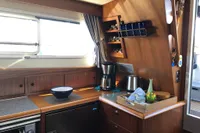 Cozy kitchen area in a 2007 Nimbus 380 Commander yacht with wooden cabinetry and appliances.