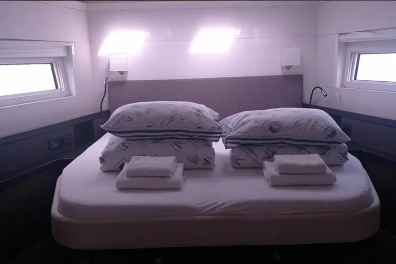 Penultimo Yacht Photos Pics Luxurious bedroom interior of 2021 Beneteau Oceanis Yacht 62 with neatly arranged bedding.