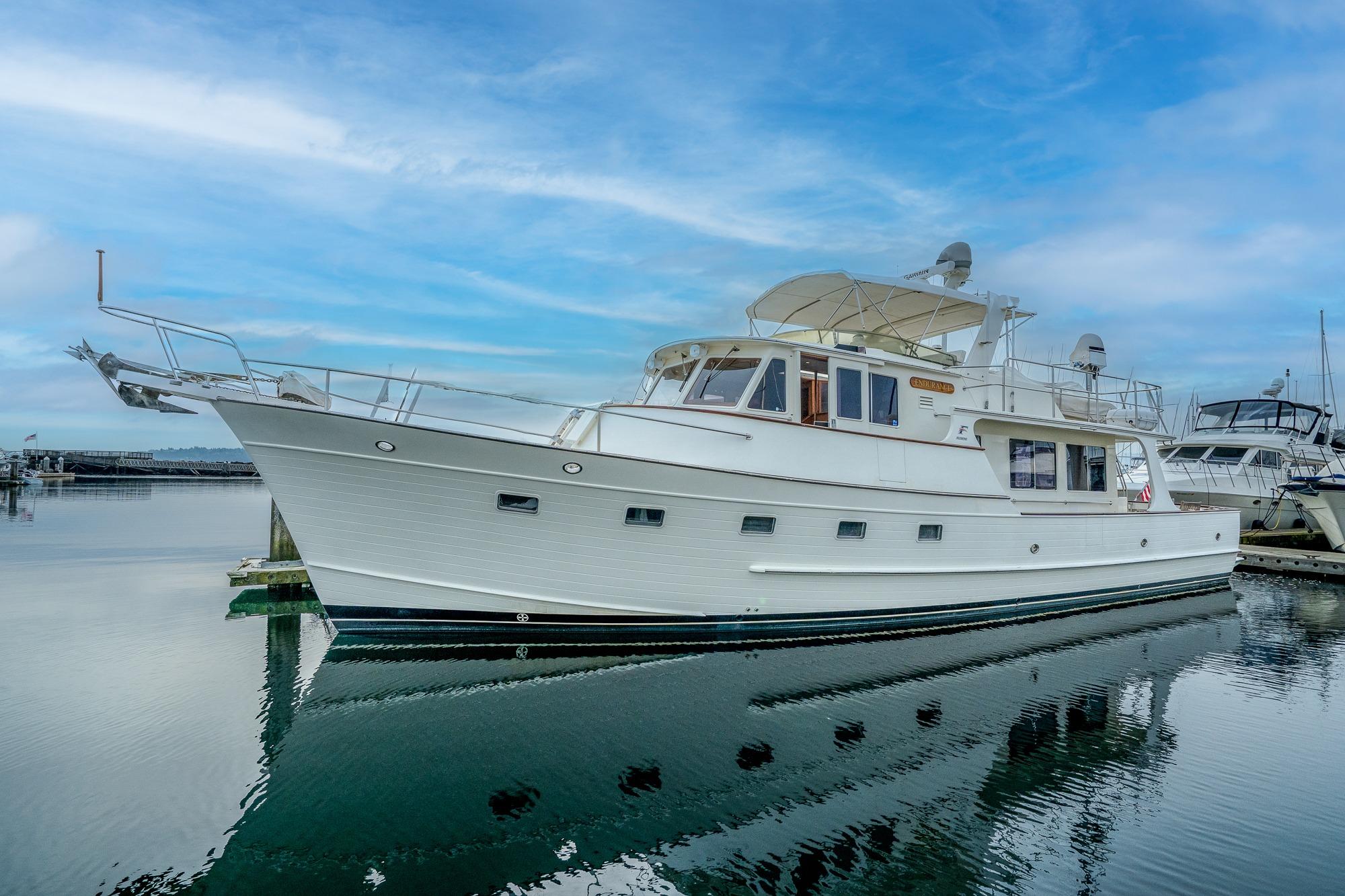 2001 Fleming 55 Pilothouse yacht docked on calm water under blue sky.