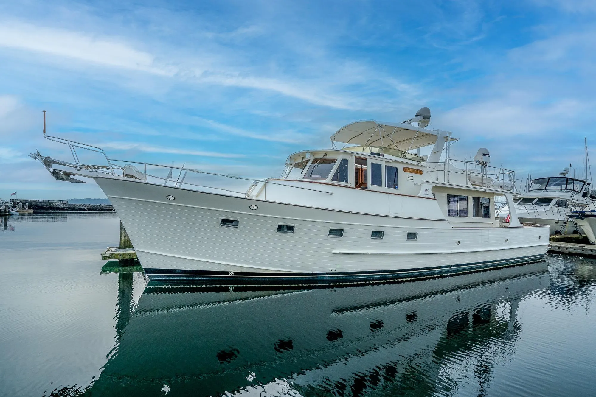 2001 Fleming 55 Pilothouse yacht docked on calm water under blue sky.