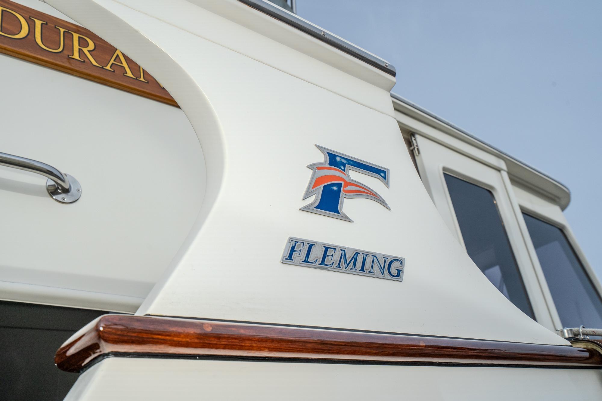 2001 Fleming 55 Pilothouse yacht with logo and wooden trim detail.