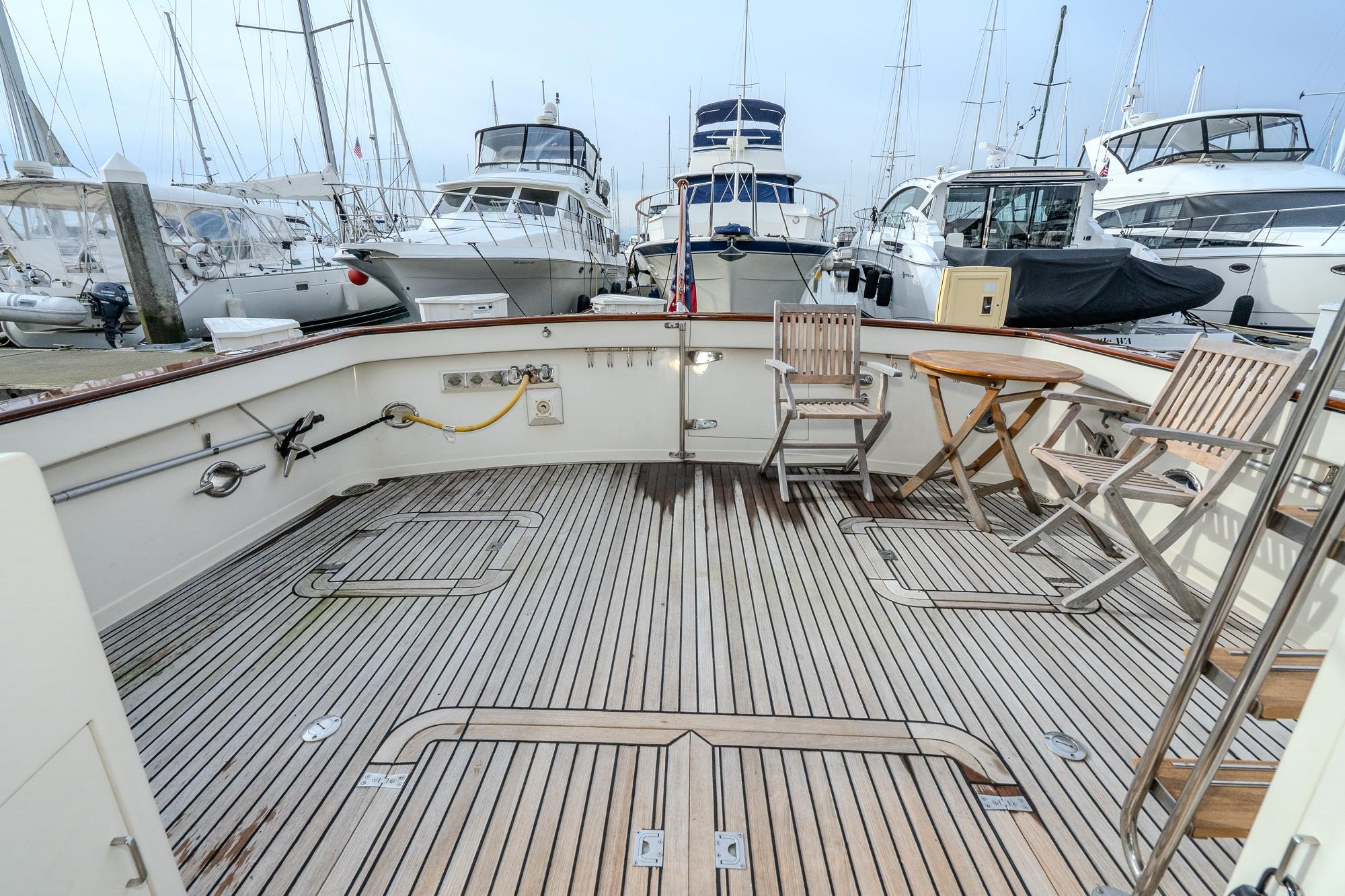 Spacious deck of a 2001 Fleming 55 Pilothouse yacht, featuring wooden chairs and table.