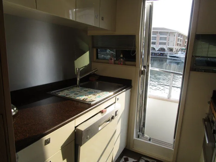 M/y Tivella Yacht Photos Pics Compact yacht kitchen with sink, countertop, and marina view through open door. VZ 68, 2009 model.