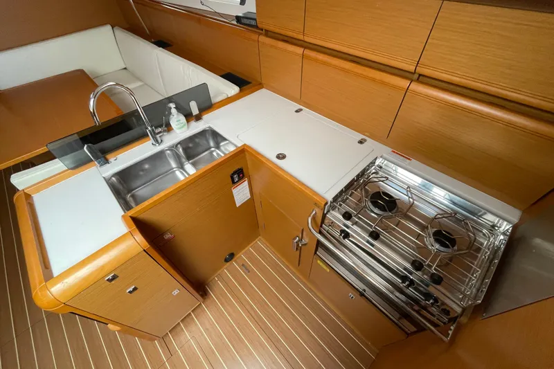 Eclipse Yacht Photos Pics 2014 Jeanneau Sun Odyssey 439 yacht kitchen with stove, sink, and wooden cabinetry.