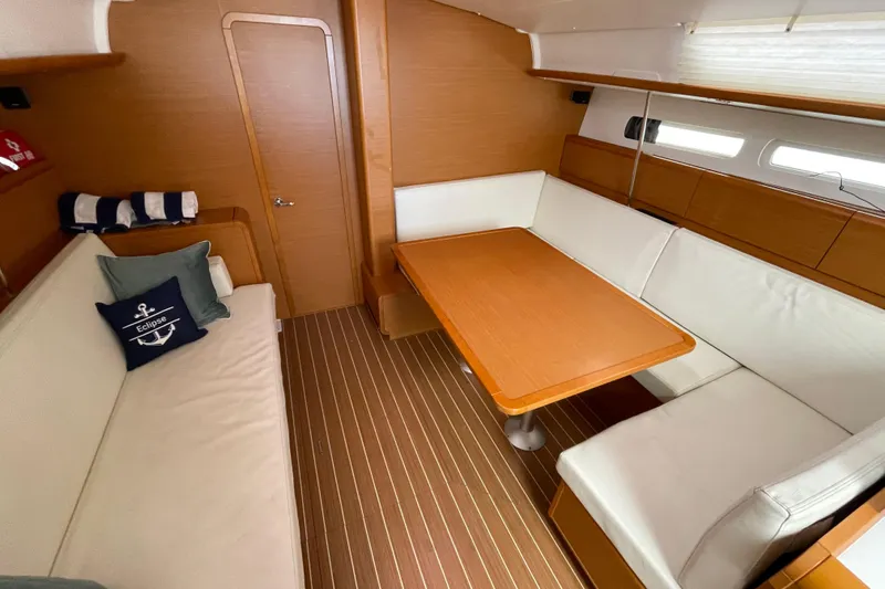 Eclipse Yacht Photos Pics Interior of 2014 Jeanneau Sun Odyssey 439 sailboat with cozy seating and wooden table.