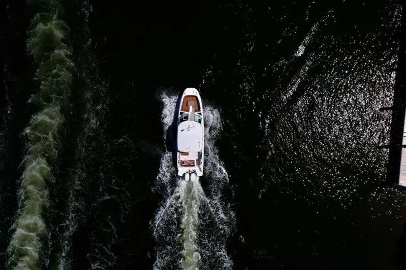 Getting There Yacht Photos Pics Aerial view of 2017 Boston Whaler Vantage 320 cruising on dark water.