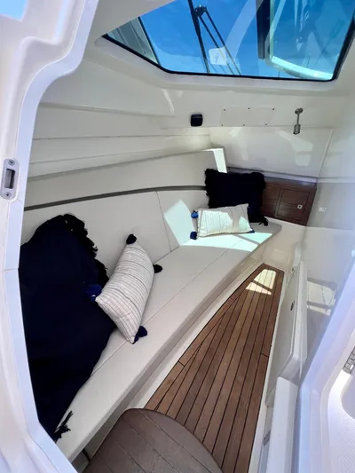 Getting There Yacht Photos Pics 2017 Boston Whaler Vantage 320 cabin interior with cushions and wood flooring.