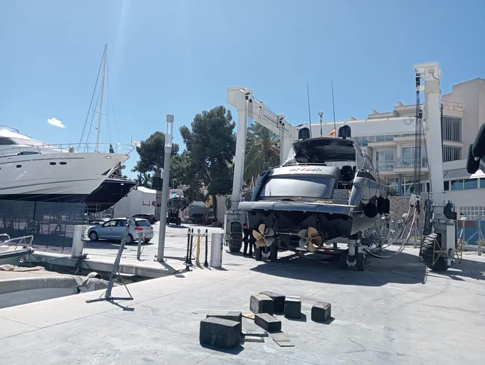 Oxygen III Yacht Photos Pics 2007 Pershing 56 yacht in a marina, elevated for maintenance under clear blue skies.
