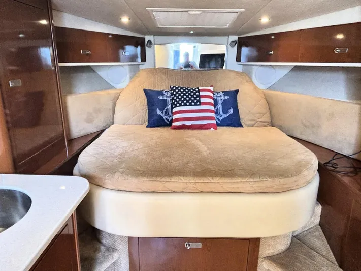 Mocaccino Yacht Photos Pics 2011 Sea Ray 350 Sundancer cabin with cozy bed, nautical decor, and wooden cabinetry.