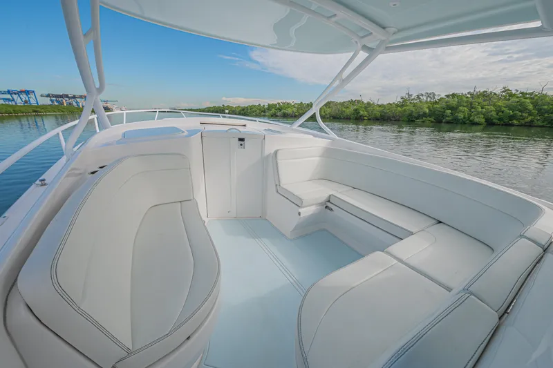  Yacht Photos Pics 2018 Intrepid 407 Cuddy boat interior with white seating, docked by lush greenery.