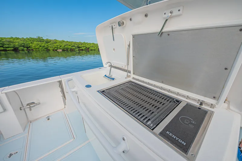  Yacht Photos Pics 2018 Intrepid 407 Cuddy boat with onboard grill and sink, docked by lush greenery.