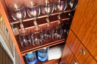 Wooden cabinet with glassware and bottles inside a 2006 Nimbus 350 Coupe boat.