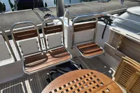 Nimbus 350 Coupe 2006 boat deck with wooden seating and table, docked at marina.