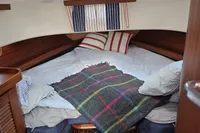 Cozy cabin interior of 2006 Nimbus 350 Coupe with striped bedding and plaid blanket.