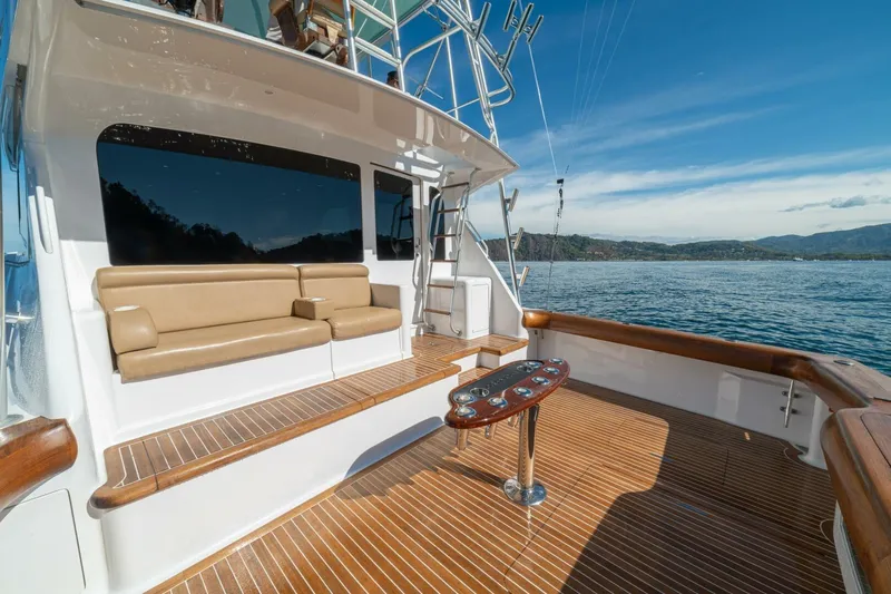 Scandaloso Yacht Photos Pics Luxurious 2006 Viking 56 yacht deck with seating, overlooking serene ocean and distant hills.