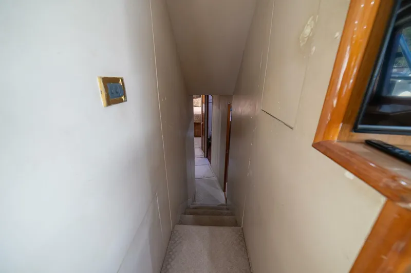 Scandaloso Yacht Photos Pics Narrow stairway inside 2006 Viking 56 yacht, featuring beige walls and wooden trim.