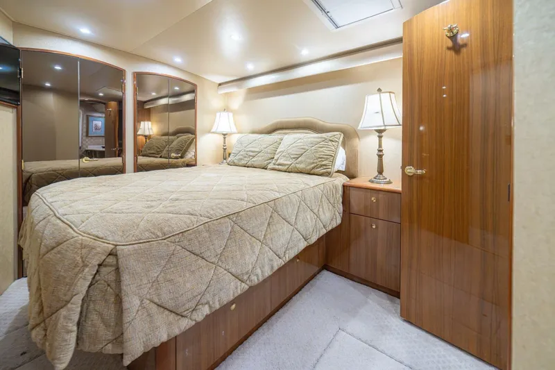 Scandaloso Yacht Photos Pics Luxurious bedroom interior of a 2006 Viking 56 yacht with elegant wood finishes and cozy lighting.