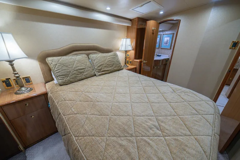 Scandaloso Yacht Photos Pics Luxurious bedroom interior of a 2006 Viking 56 yacht with elegant bedding and warm lighting.